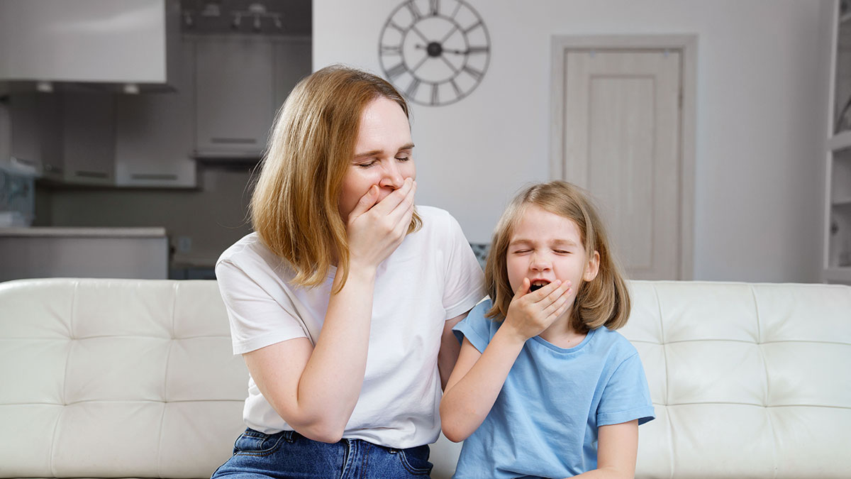 Mother and daughter yawning on a couch
